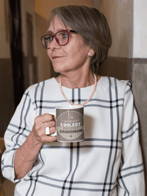 11-oz-coffee-mug-mockup-of-a-fashionable-senior-woman-leaning-against-a-wall-27453-1